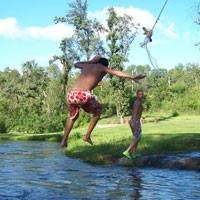 Two people using rope swing near river